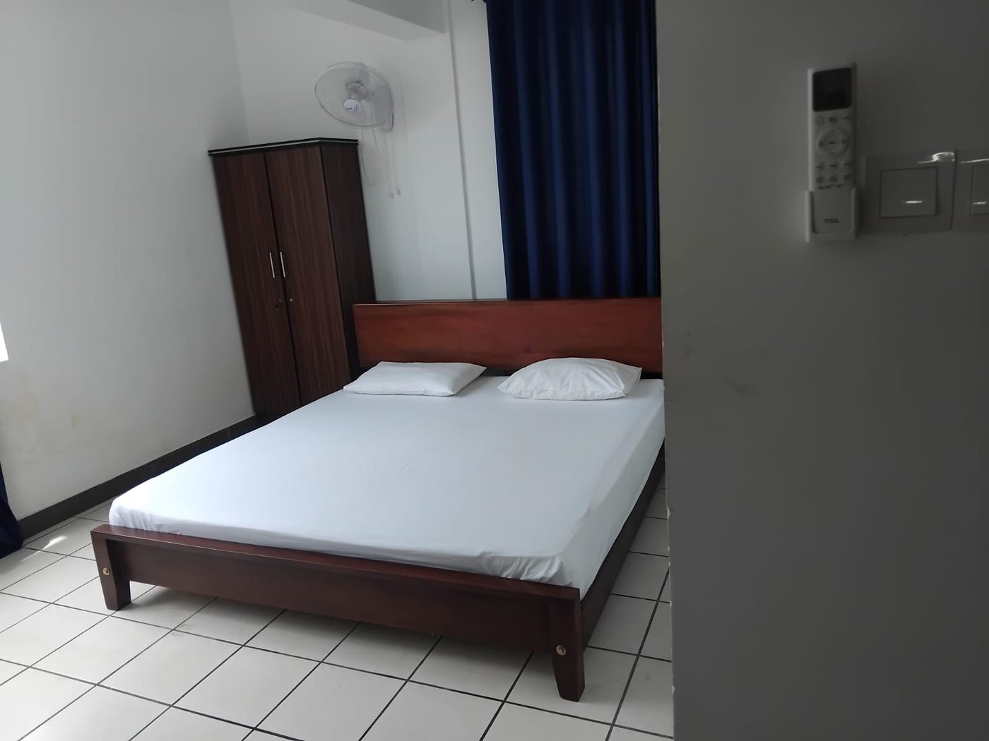 Air-conditioned double room at Ceylon City Beds with a wooden bed, wardrobe and wall fan