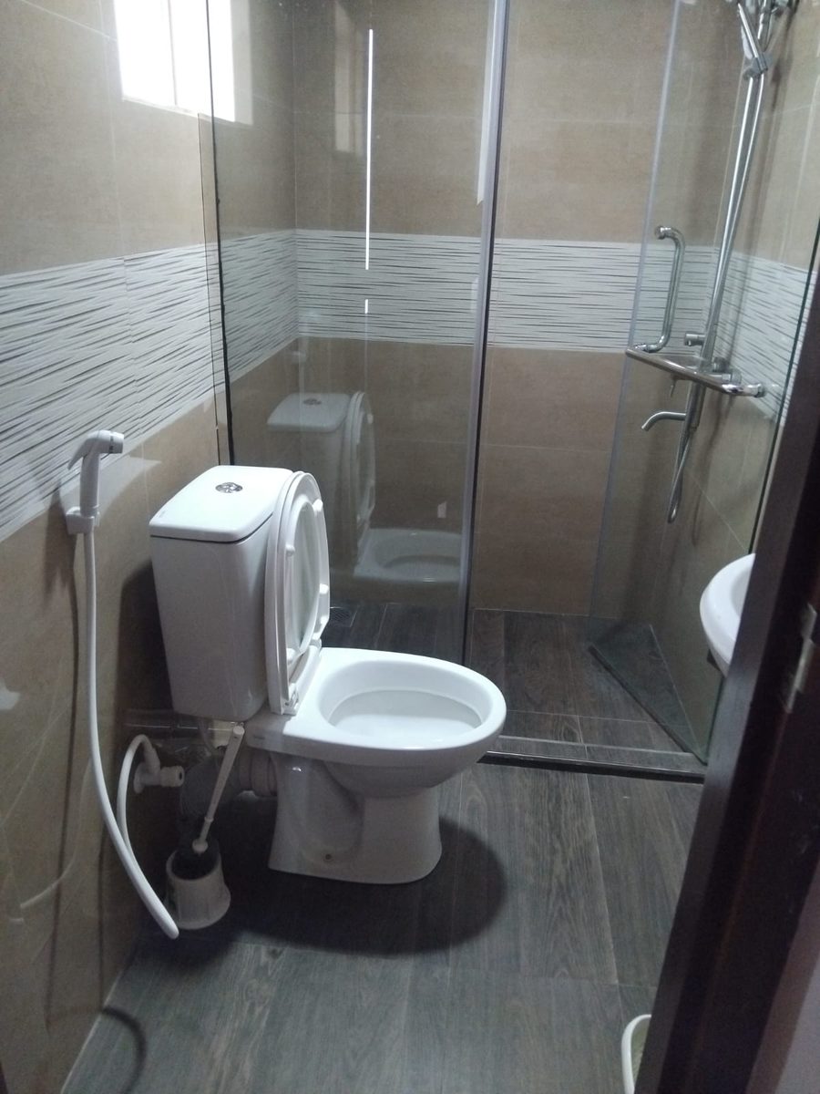 Tiled en-suite bathroom with a glass hot water shower cubicle